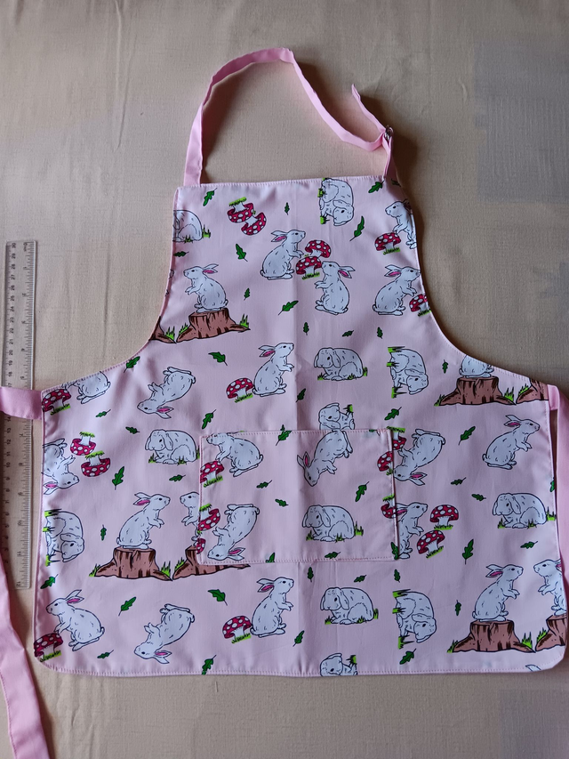Childs Kitchen Play Apron Pink Bunnies Patterned Cotton Fabric with Front pocket and pink lining, waist ties and adjustable neck ties 