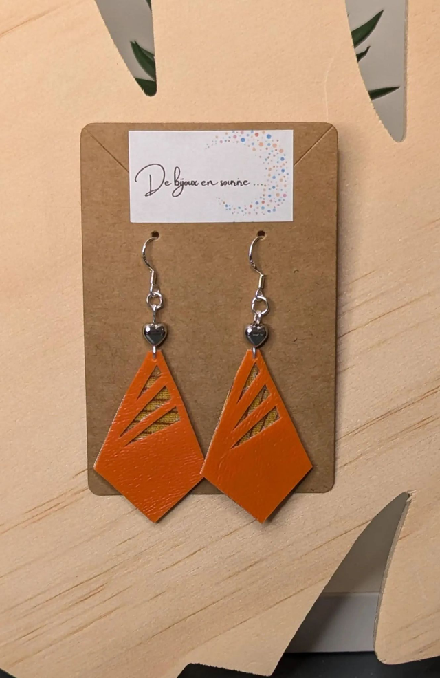 Boucles d'oreilles en similicuir et du tissus enduit, des perles métalliques de forme géométrique, le fermoir est en argent. 