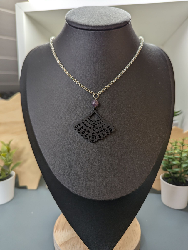 Collier court avec une chaine de couleur argent une perle naturelle et un pendentif en bois noir. 