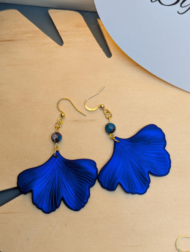 Boucles d&#039;oreilles avec pendentifs en forme de feuilles de couleur bleu métallisé avec des perles de jaspe sédiment de mer.