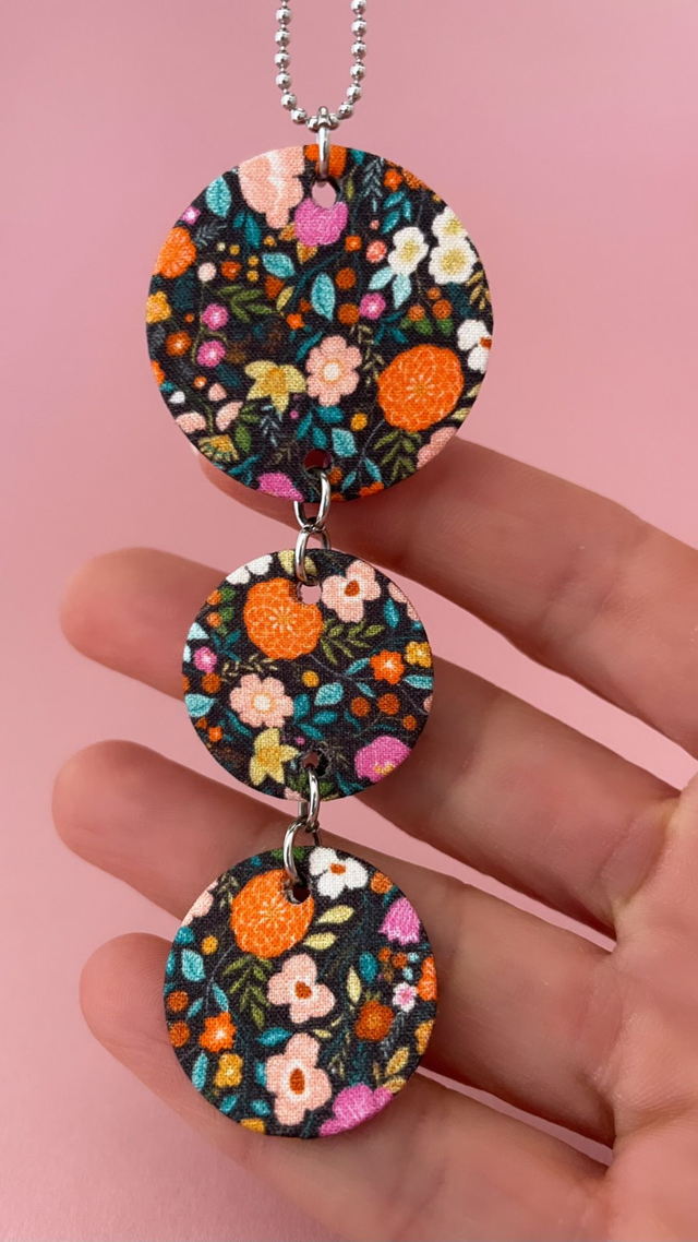 Collier avec pendentif en carton et tissu fleuri, composé de trois cercles, collection "1001 fleurs", fond noir et motifs fleuris multicolores