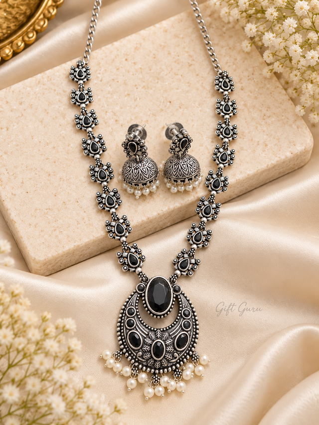 Traditional Indian ethnic jewellery set features an oxidised silver finish with intricate floral motifs and is embellished with black stone 