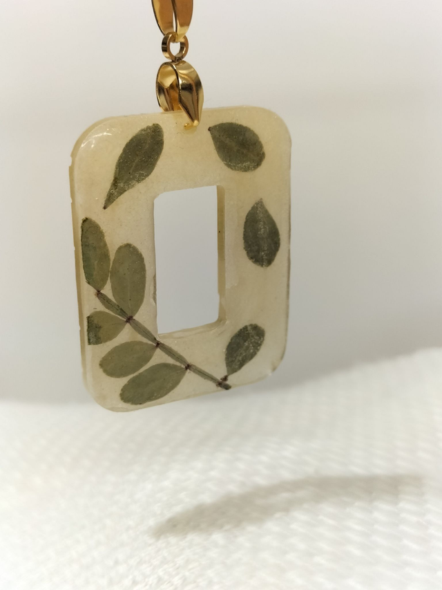 Pendentif géométrique doré et feuilles séchées