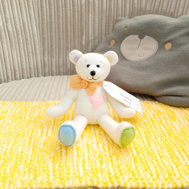Joy. Small size, handmade teddy bear. UKCA. Tray base packaging. Standard Wool Felt. White. Pastel rainbow. Orange. Pink. Yellow. Green. Blue. Purple.