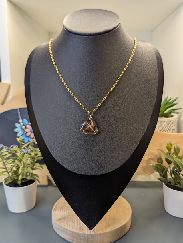 Collier avec pendentif en résine transparente te marron en forme de triangle.