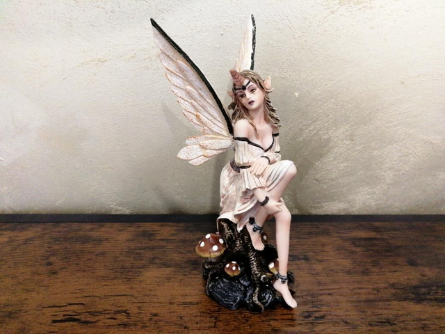 Fee assis sur un tronc 