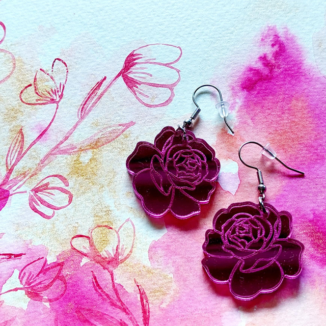 Ruusu. Akryylilasi-korvikset (pari), koukut kirurginterästä. Pituus koukun kanssa 5cm, max leveys 3cm. Lahjarasiassa.