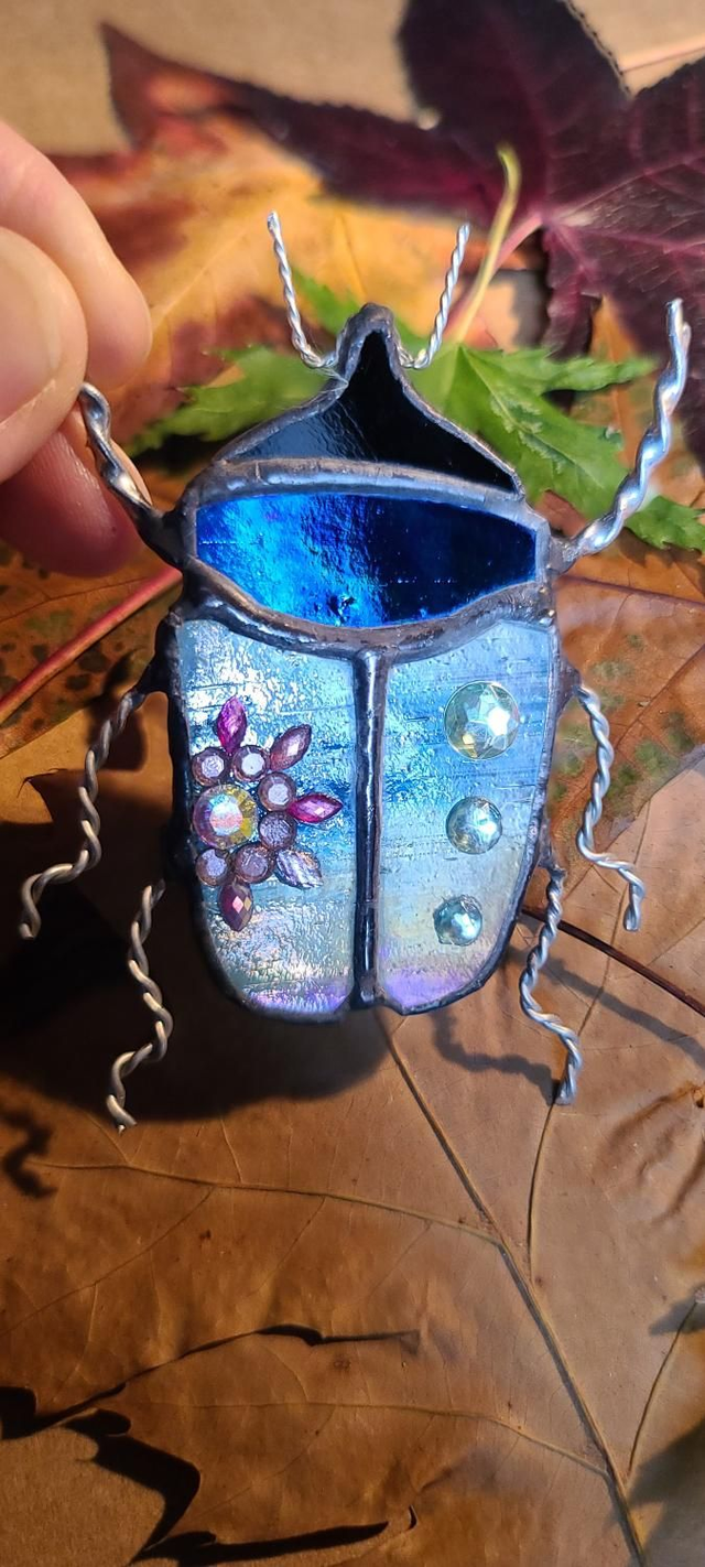 Scarabée en verre, au corps bleus iridescents et à la tête noire, en Tiffany et monté en magnet. 