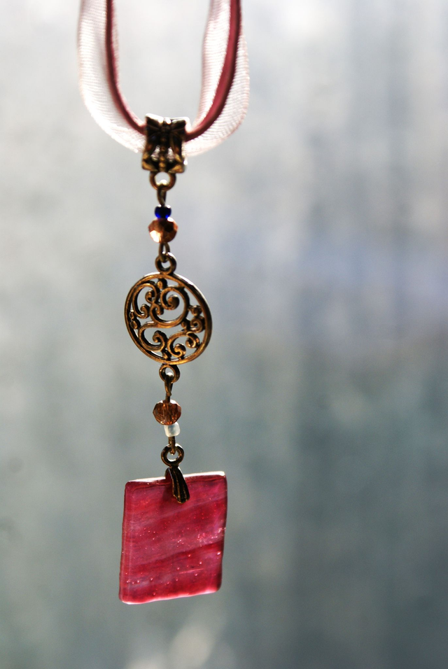 Pendentif en verre rouge chamarré et texturé. Chaîne en coton rose. 