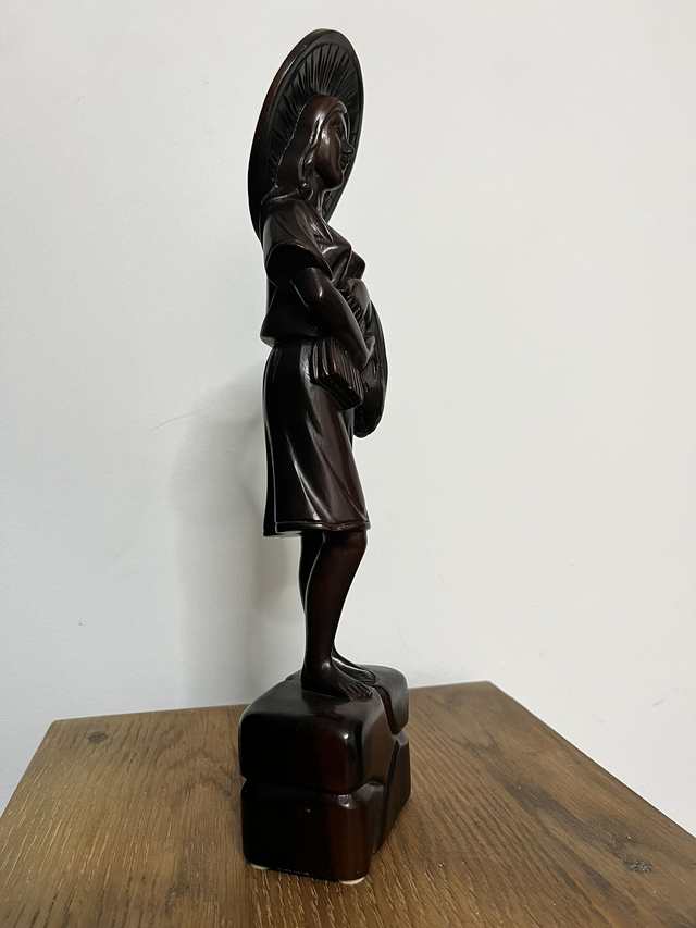 Wooden statue of a Filipino female farmer, with a hat, holding harvested rice.