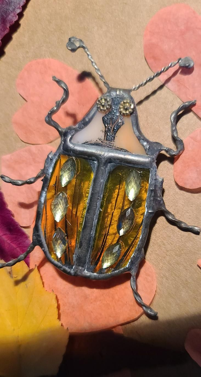 Scarabée en verre, au corps jaune transparent et à la tête rosée opalescente, en Tiffany, monté en broche. 