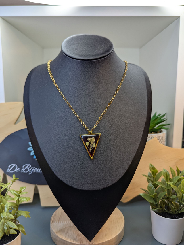 collier mi long de couleur or avec un pendentif en résine rouge et fleur naturelle blanche. 