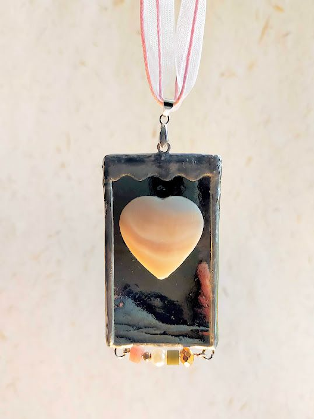 Pendentif en verre doré iridescent, sertis en Tiffany et chaîne en coton rose.