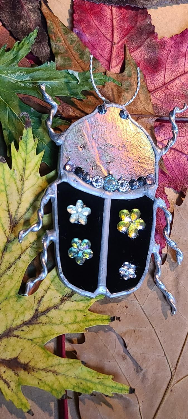 Scarabée en verre, au corps noir et à la tête argentée iridescente, en Tiffany et monté en  broche. 