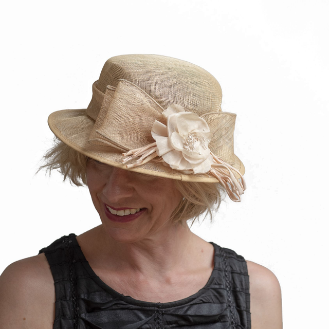 Beige juhlahattu nauhalla ja kukkasomisteella