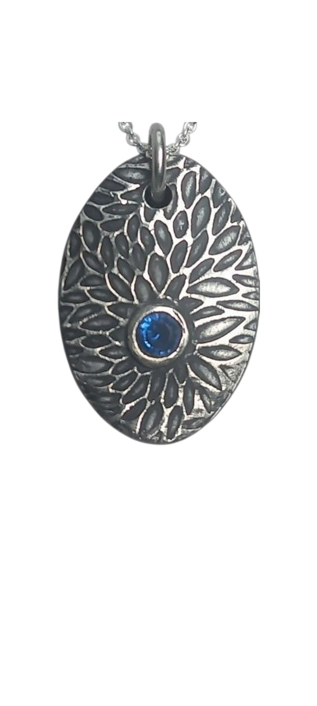Textured silver oval pendant with blue gem