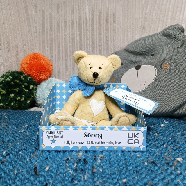 Sonny. Small size, handmade teddy bear. UKCA. Tray base packaging. Standard Wool Felt. Yellow marl. Blue. Cream. Straw yellow.