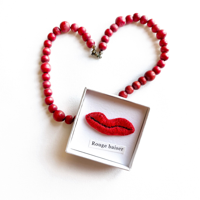 Bouche rouge brodée présentée dans petite boîte blanche