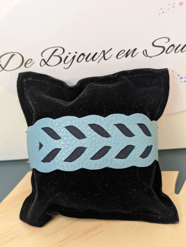 Bracelet manchette en cuir bleu, avec du tissus enduit bleu foncé (résistant), une chaine argentée. Le fermoir est de couleur argent.