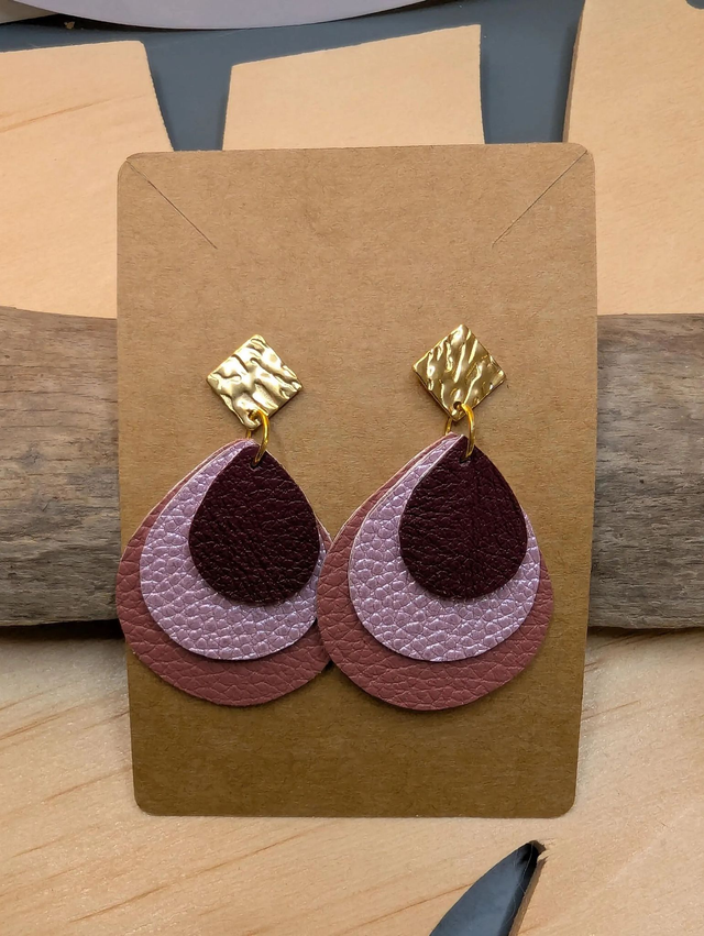 Boucles d'oreilles en cuir en forme de goutte avec un dégradé de rose/violet le derrière est en blanc. Le fermoir en clou carré est de couleur doré.