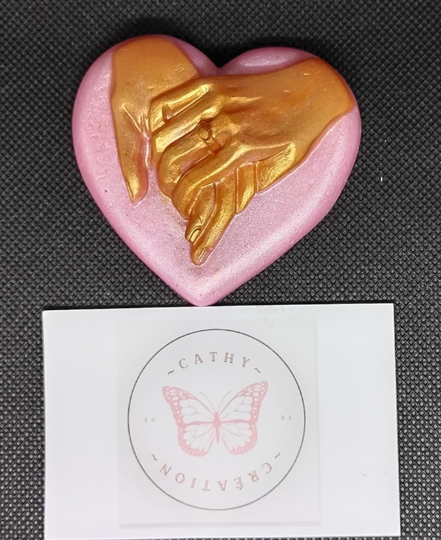 Mains enlacées dorées sur coeur rose