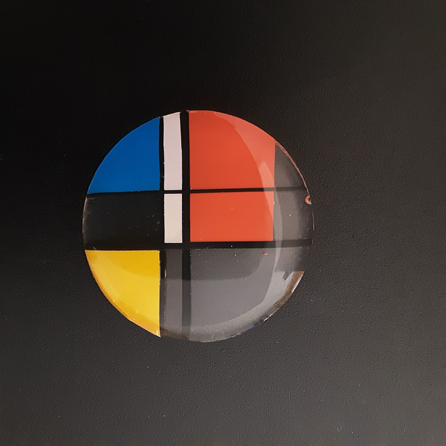 Broche ronde collection graphique-fond transparent-décor blanc-bleu-jaune-liseré noir