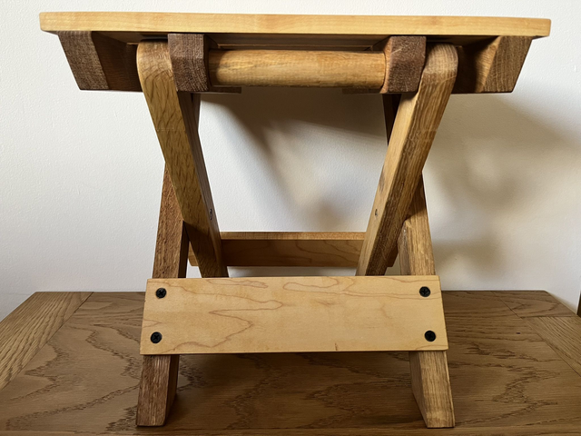 Wooden, folding camping stool made of oak and maple wood.
