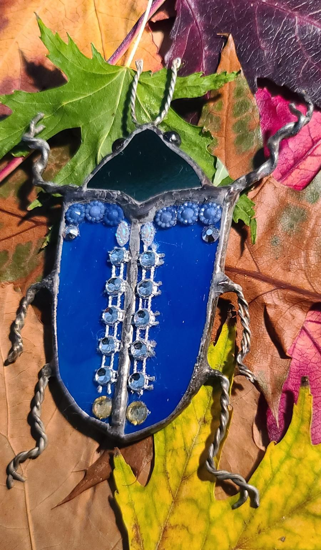 Scarabée en verre, au corps bleu opalescent et à la tête noire, en Tiffany et monté en magnet.  
