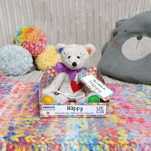 Happy. Miniature size, handmade teddy bear. UKCA. Tray base packaging. Standard Wool Felt. Beige. Yellow. Blue. Green. Orange. Purple. Red.
