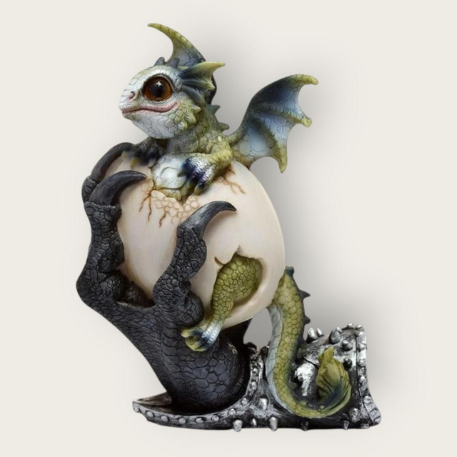 Bébé dragon sortant de son œuf dans des griffes 