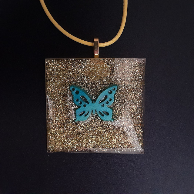 Pendentif grand carré collection mouna paillette fond doré scintillant et papillon turquoise incrusté