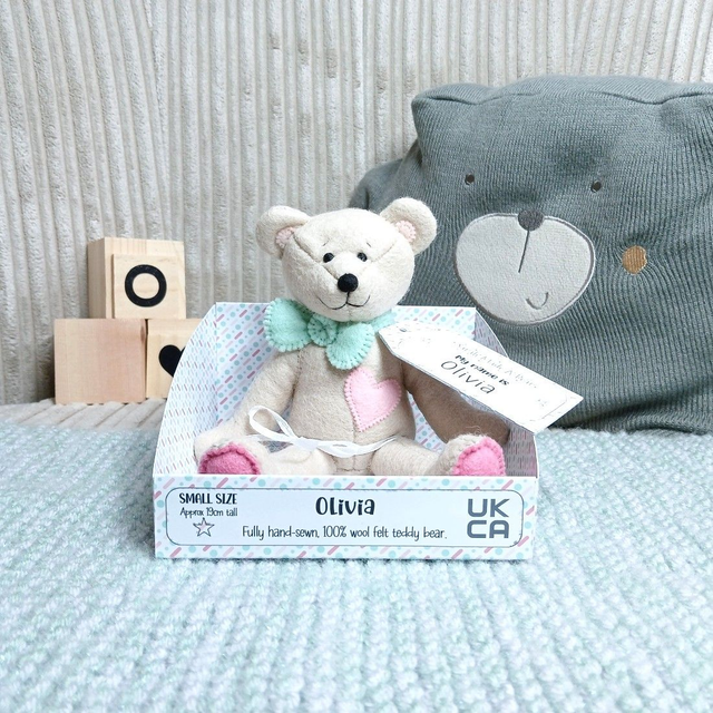 Olivia. Small size, handmade teddy bear. UKCA. Tray base packaging. Standard Wool Felt. Beige. Pastel green. Pinks.