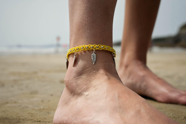 Bracelet de cheville en micro-macramé jaune et breloques plumes
