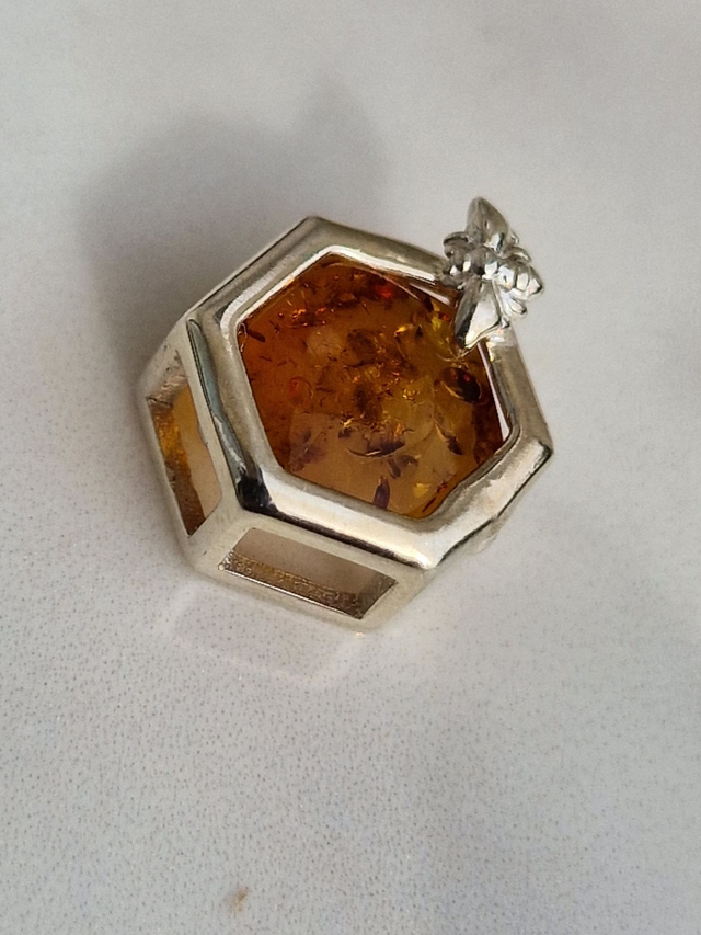 Baltic natural amber honeycomb pendant approx 11x10mm in a honeycomb silver setting with a feature mini bee. No chain