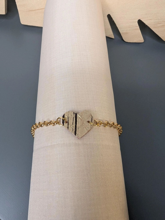 Bracelet en chaine de couleur or en forme de cœur en cuir et tissus enduit rouge, le fermoir est de couleur or. 