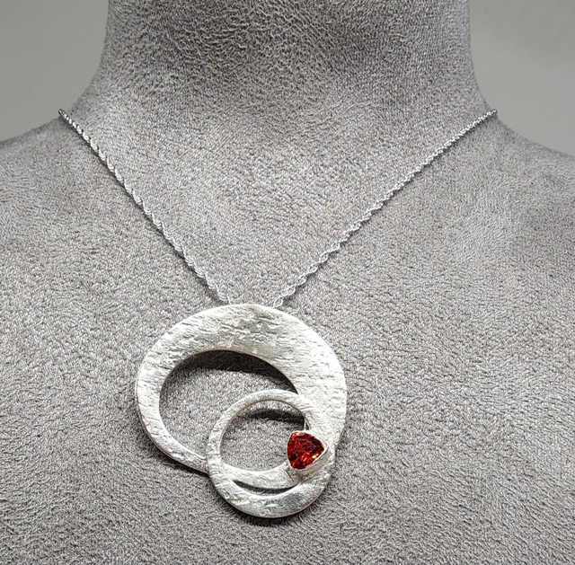 Orbital ring pendant with a deep orange cubic zirconia on silver necklace 