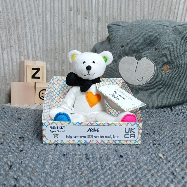 Zeke. Small size, handmade teddy bear. UKCA. Tray base packaging. Standard Wool Felt. White. Black. Bright blue, pink, green &amp; yellow.
