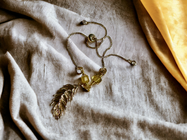 Gold slider bracelet with feather charm