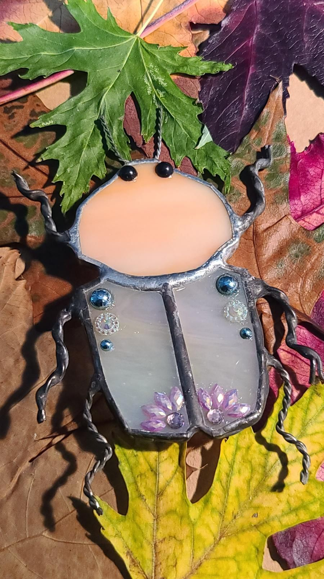 Scarabée en verre, au corps blanc iridescent et à la tête  rosée opalescent, en Tiffany et monté en broche.  