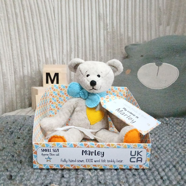 Marley. Small size, handmade teddy bear. UKCA. Tray base packaging. Standard Wool Felt. Fluffy beige. Bright blue. Yellow. Orange.