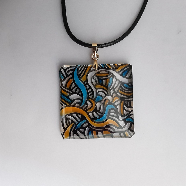 Pendentif carré fond transparent entrelacs noir et touches de bleu et jaune translucide