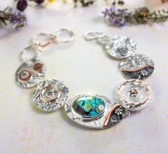 Pulsera artesanal en plata con turquesa iraní y detalles en cobre.