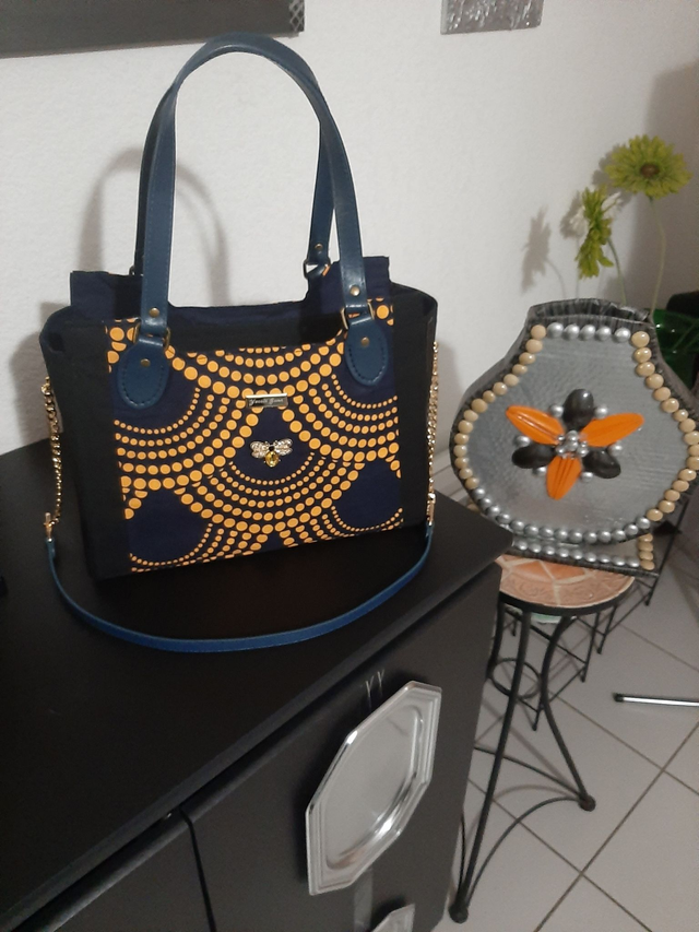 sac noir  bandoulière en tissu wax doré	avec décoration  broche abeille crystal vert  poche arrière  zipée		 		