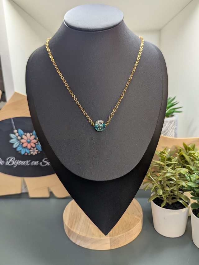collier mi long avec chaine de couleur or et pendentif en verre de couleur bleu foncé.