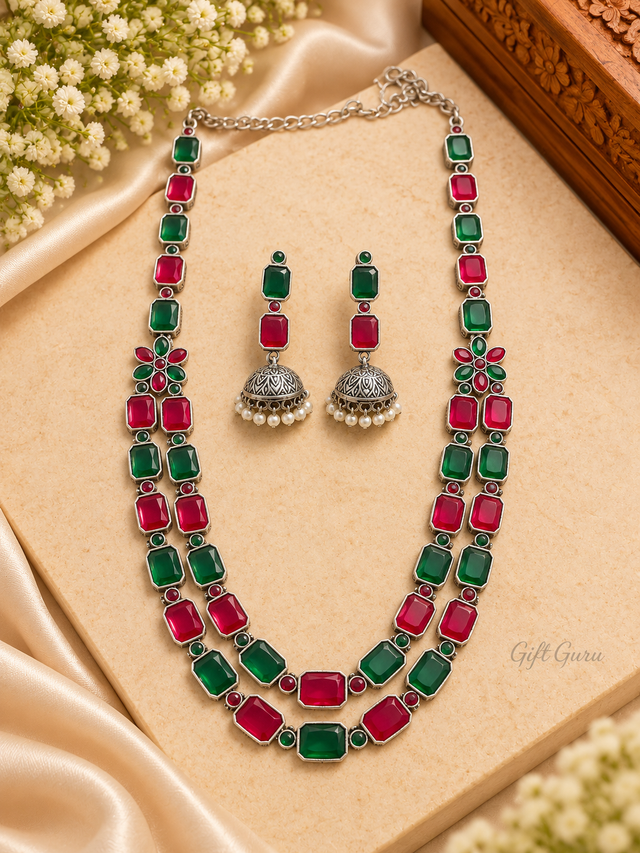 Double-layered oxidised silver-toned ethnic necklace and jhumka earring set adorned with vibrant ruby-red and emerald-green geometric stones