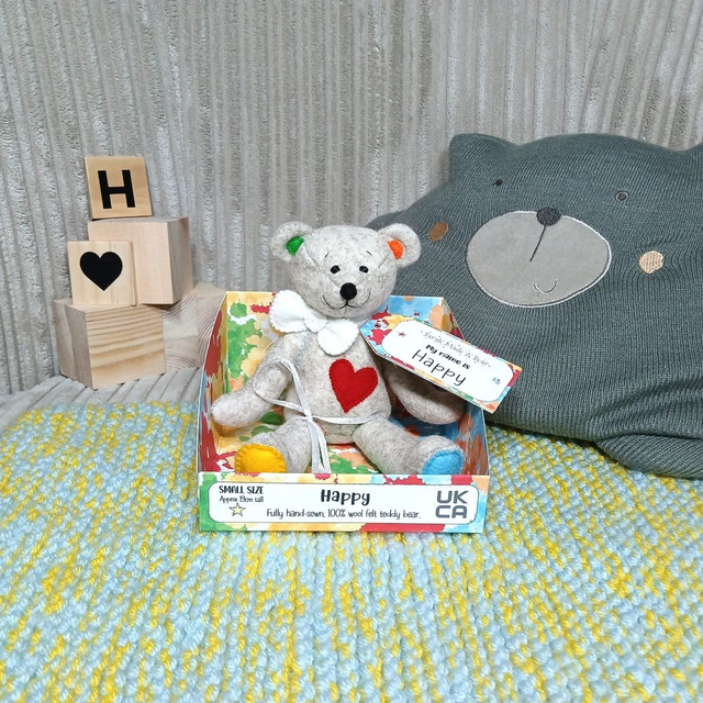 Happy. Small size, handmade teddy bear. UKCA. Tray base packaging. Standard Wool Felt. Beige. Bold rainbow. White. Blue. Green. Orange. Red. Yellow. 