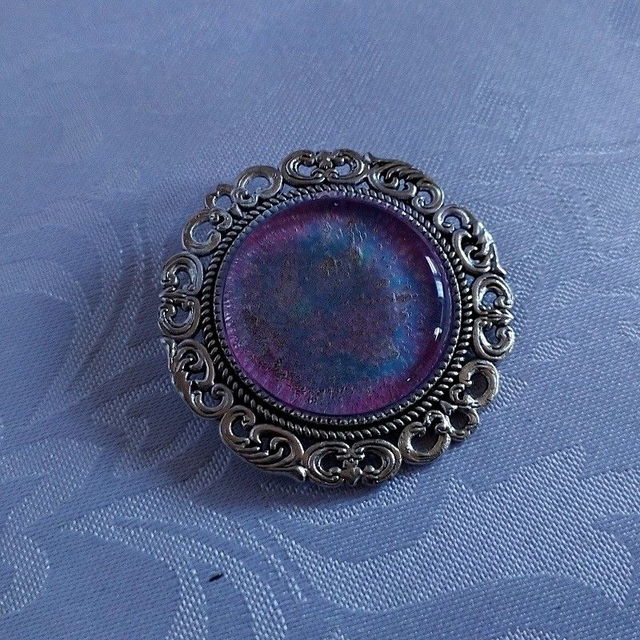 Broche cabochon verre brillant dans le noir.