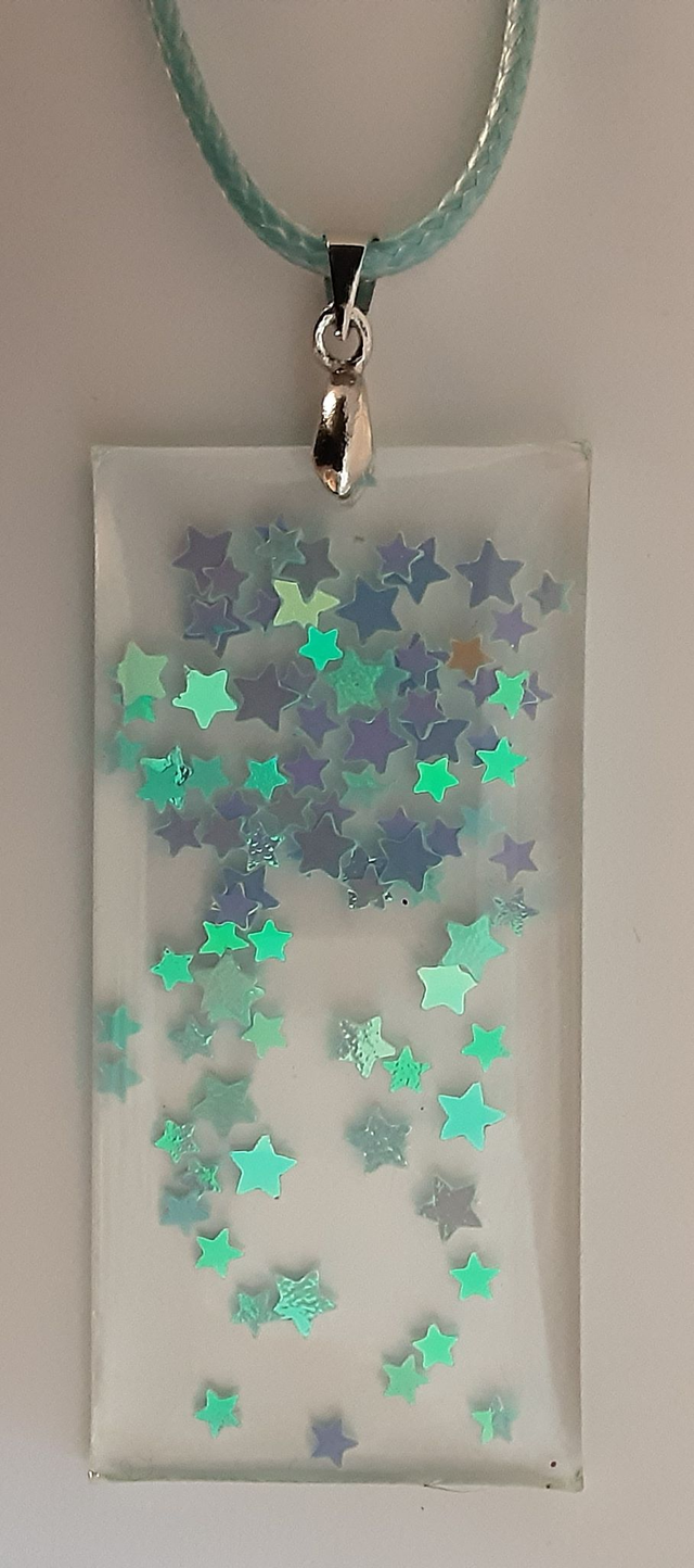 Pendentif grand rectangle collection Mouna paillette fond transparent parsemé de petites étoiles bleu irisées