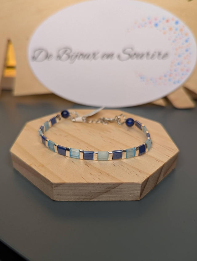 Bracelet en perles plate en verre bleu et perles d'espacement en métal argenté. Le fermoir et le chaine fermoir sont en argent.
