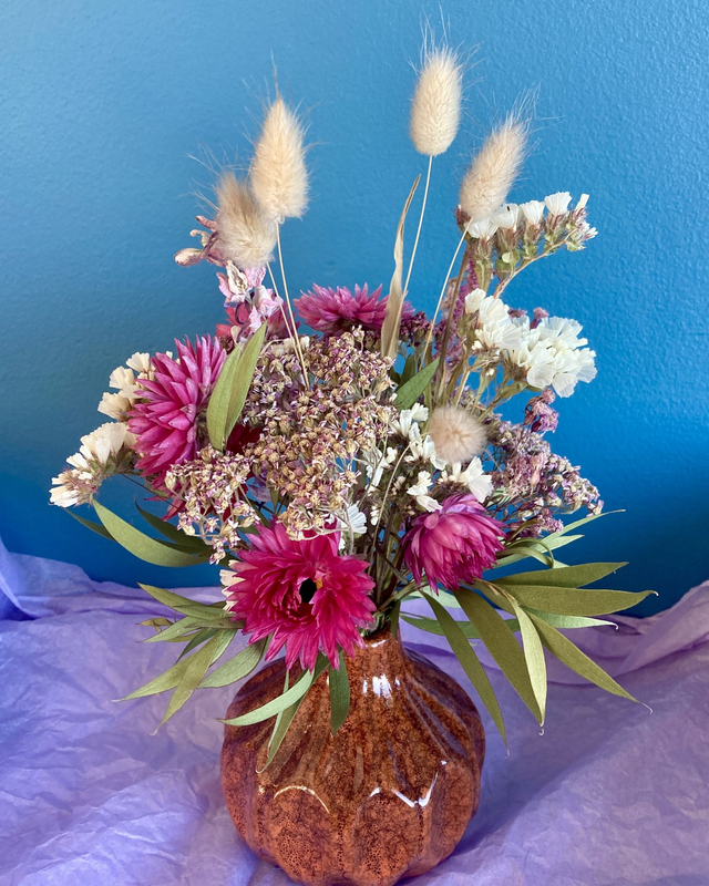 Local dried flower arrangement in rusty brown glazed vase